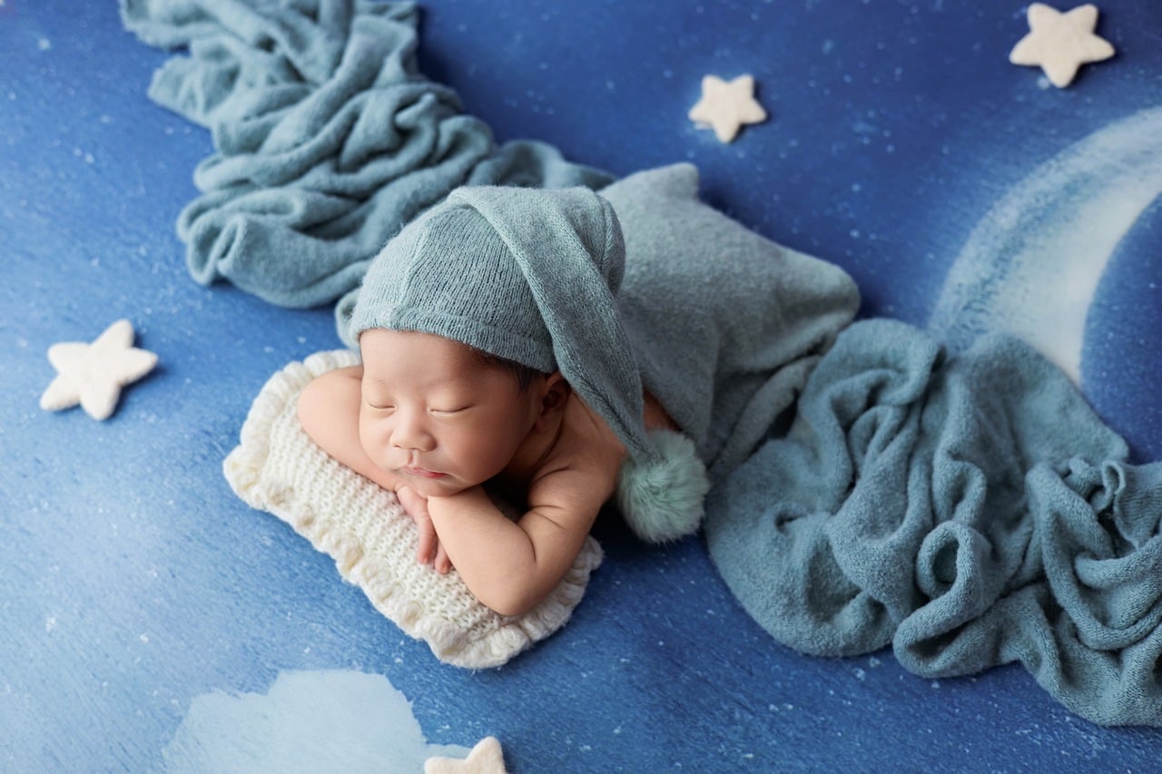 newborn, creative photography, sleeping baby, blue color, moon and stars, baby studio, peaceful, baby hat, swaddle wrap, moonlight, newborn in studio, soft fabric, baby photography, fabric with stars, night sky, newborn with hat, snug baby, baby portrait, dreamy, newborn pose